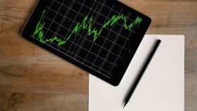Un gráfico bursátil con ganancias en una tableta y un escritorio.