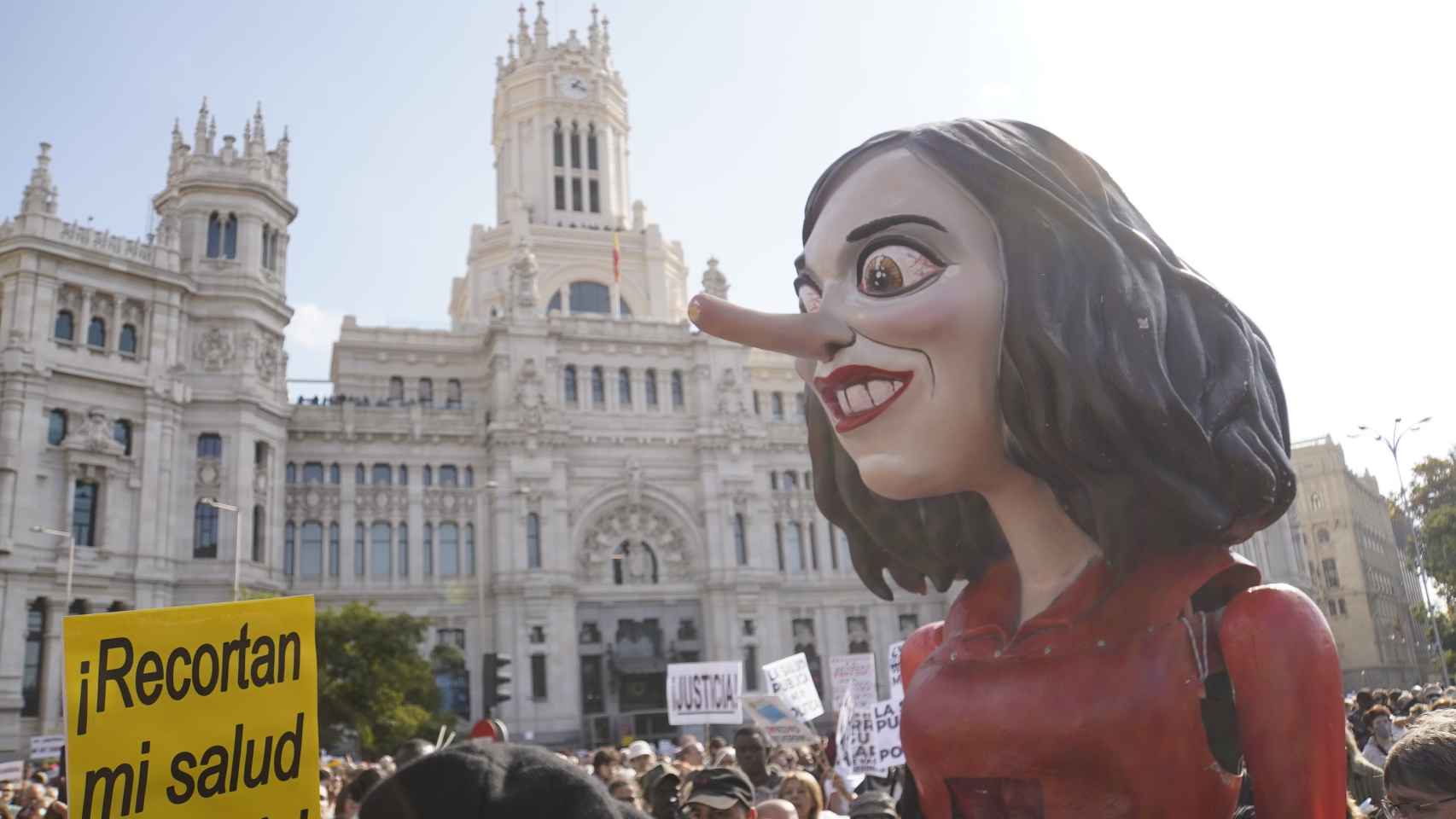 Un busto caricaturizado de Ayuso recorre la manifestación por la sanidad pública.