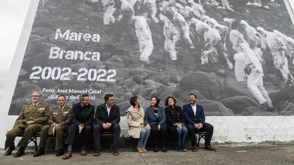 La ministra de Política Territorial, Isabel Rodríguez (4d), y la alcaldesa de Camariñas, Sandra Insua Rial (3d), posan bajo un a los voluntarios durante el acto institucional del 20 aniversario de la catástrofe del buque Prestige, en Camariñas, A Coruña.