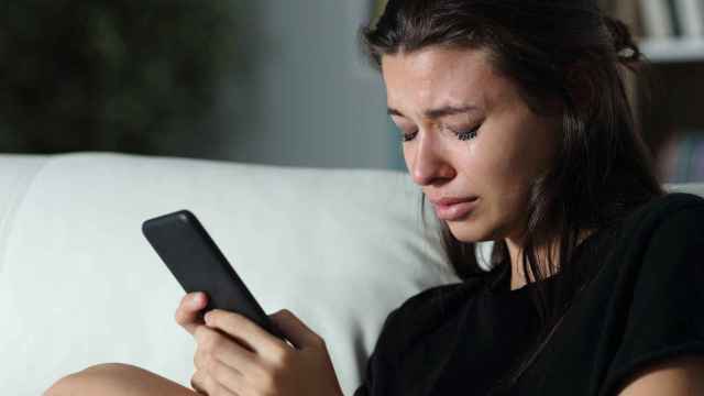 Una chica joven llora mirando su móvil.