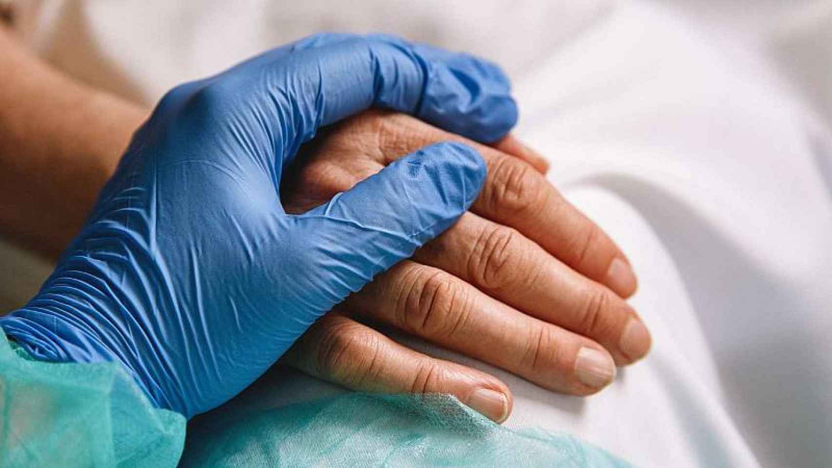 Un sanitario sosteniendo la mano de una persona durante la pandemia.