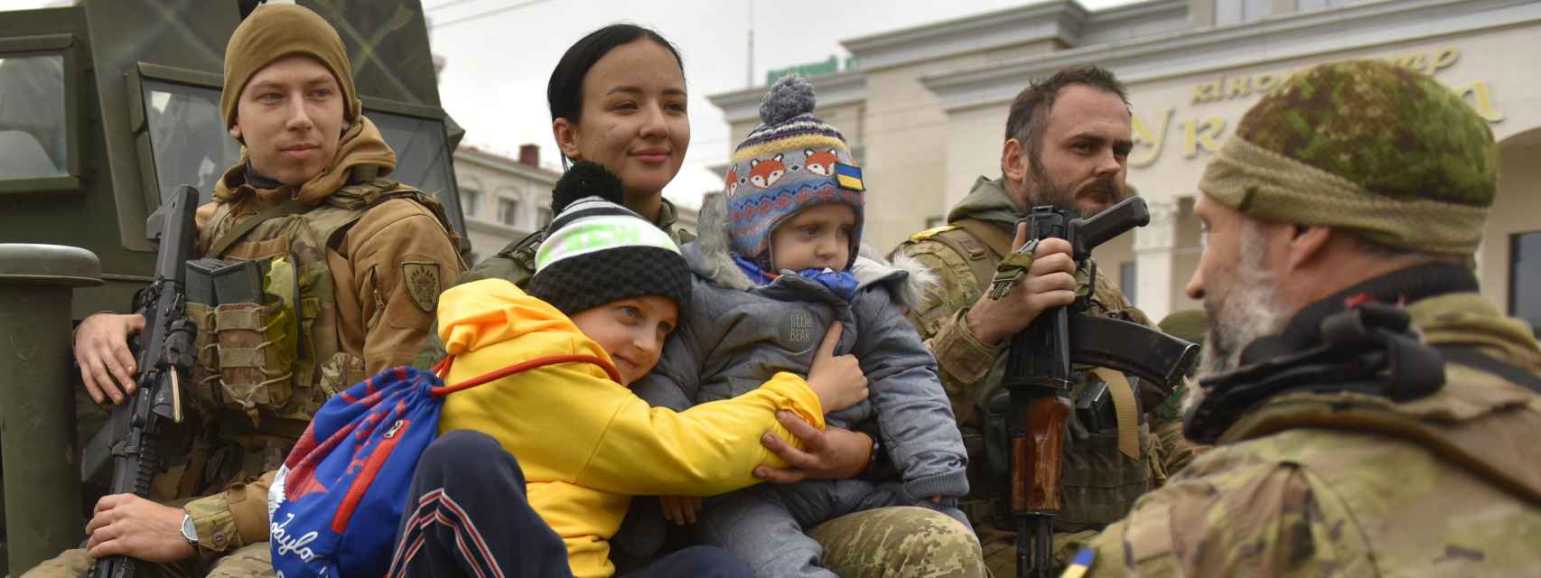 Una militar ucraniana abraza a unos niños en la plaza central de Jersón, en Ucrania.
