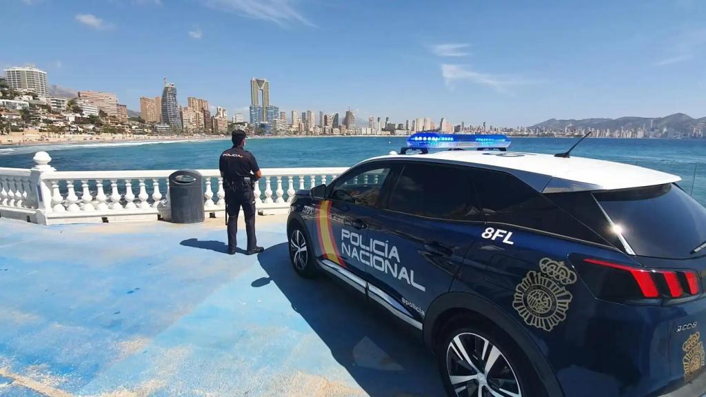 Un agente y un coche de la Policía Nacional en Benidorm, en imagen de archivo.