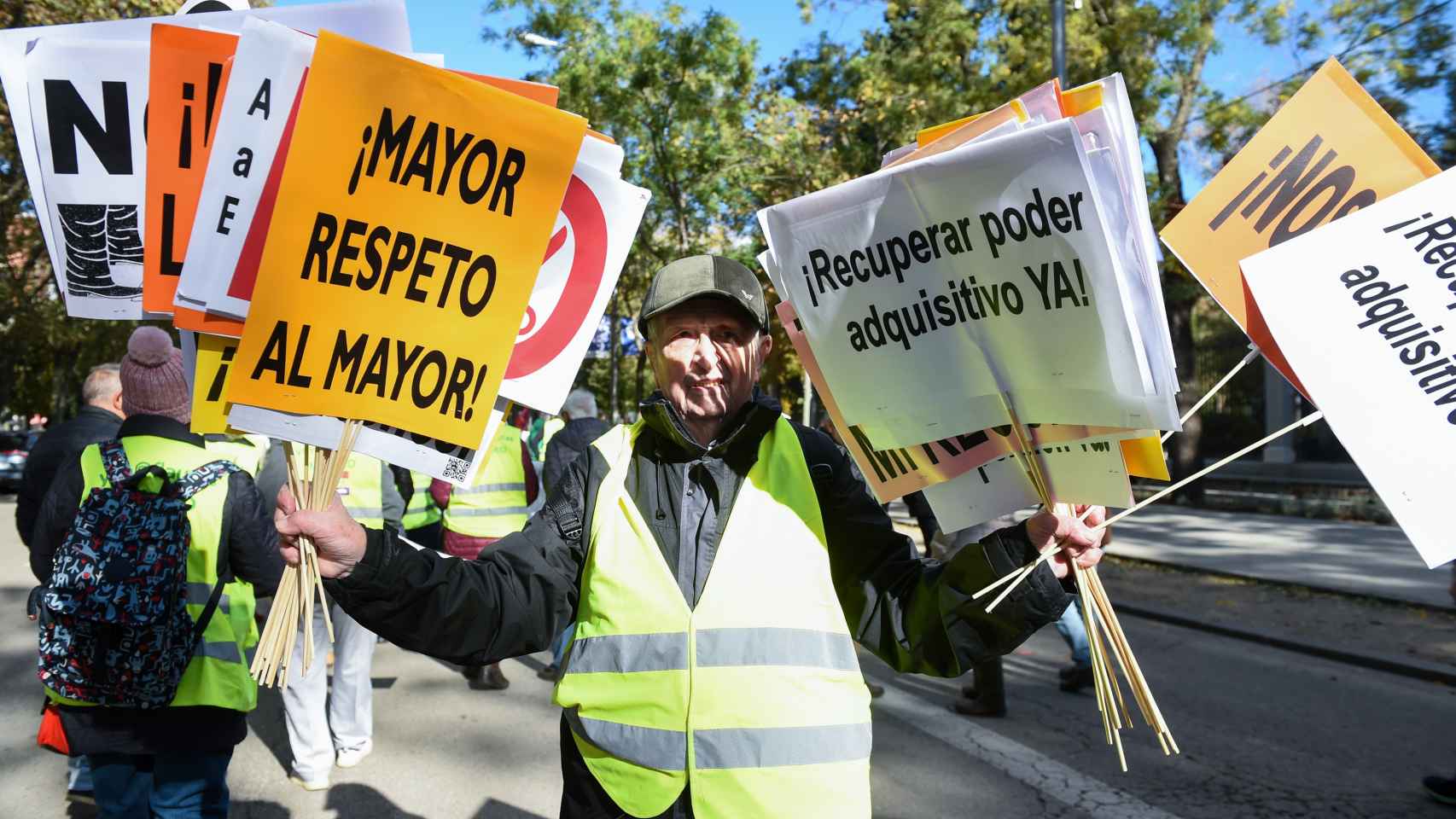 Un hombre sujeta varias pancartas en una manifestación para exigir una mejora de las pensiones y de los salarios acordes al IPC real celebrada a 19 de noviembre de 2022 en Madrid.