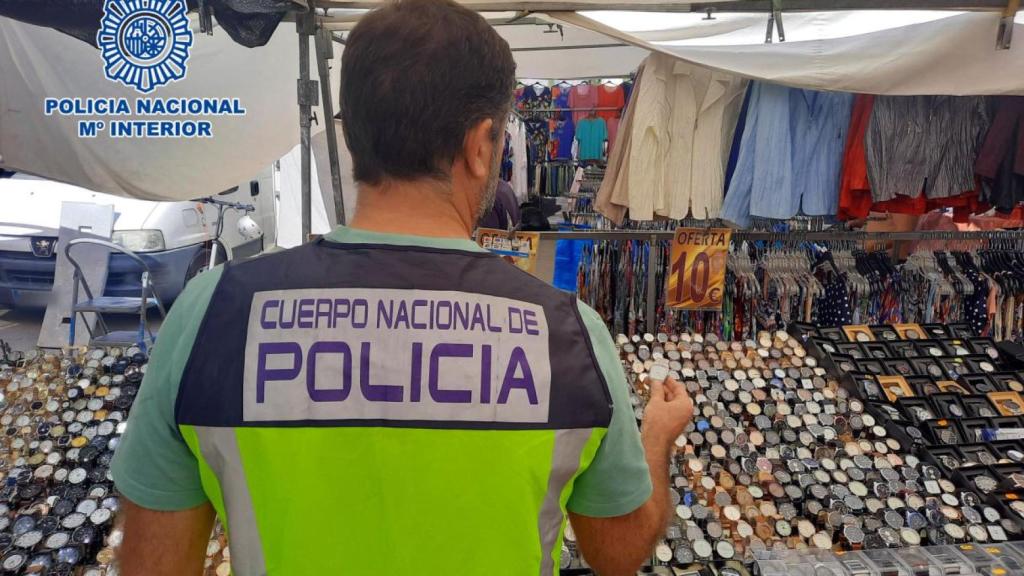 Un agente de la Policía Nacional inspecciona parte del material intervenido en el mercadillo.