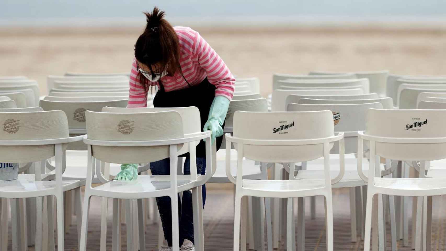 Una mujer limpia la terraza de un restaurante en Valencia.