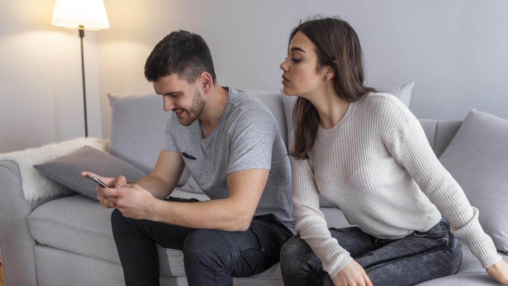 Una mujer observa el móvil de su pareja.