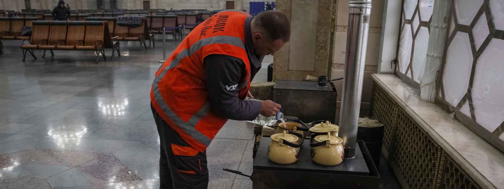 Un trabajador prepara té en una estufa de leña para los pasajeros de la estación central de trenes de Kiev.