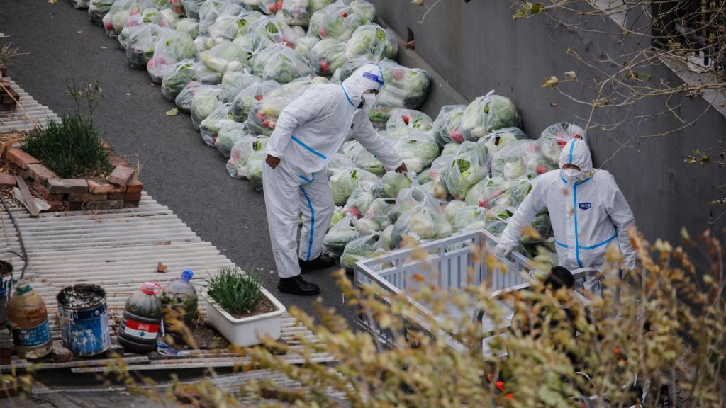 Trabajadores sanitarios preparan bolsas de verduras para los residentes confinados en Pekín.