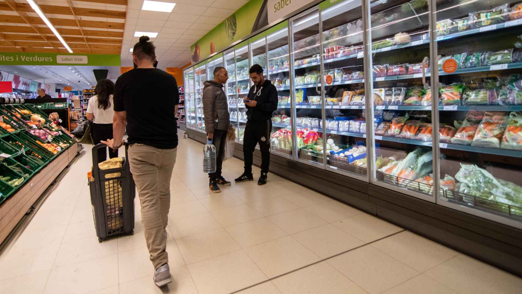 Varios consumidores, haciendo la compra en un supermercado.