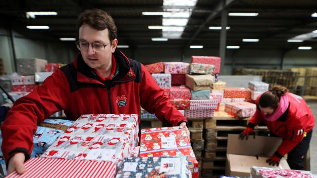 Un voluntario del programa 'Convoy navideño' carga paquetes en el almacén