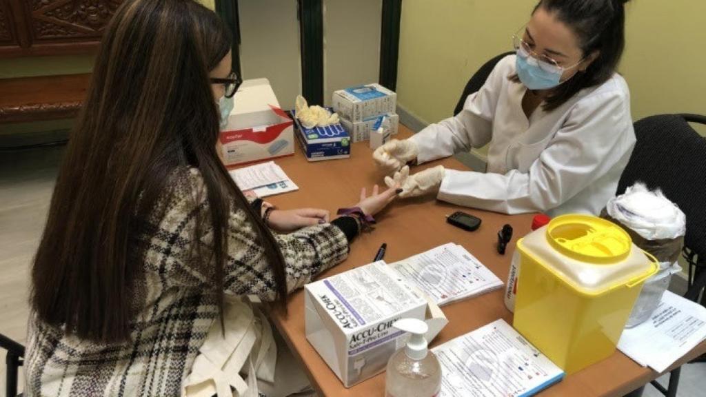 Una enfermera realiza una prueba de diaebetes a una joven.