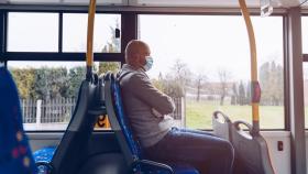 Un hombre con mascarilla en un autobús.