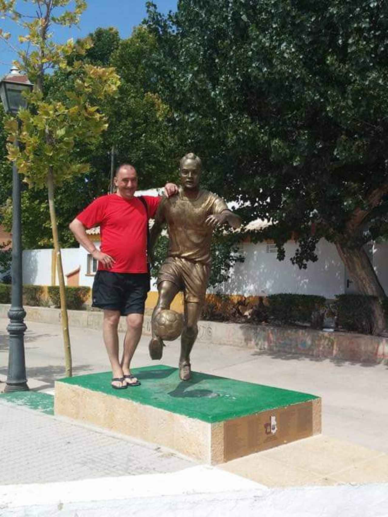 Yves José. junto a la estatua de Andrés Iniesta, en la localidad manchega de Fuentealbilla.