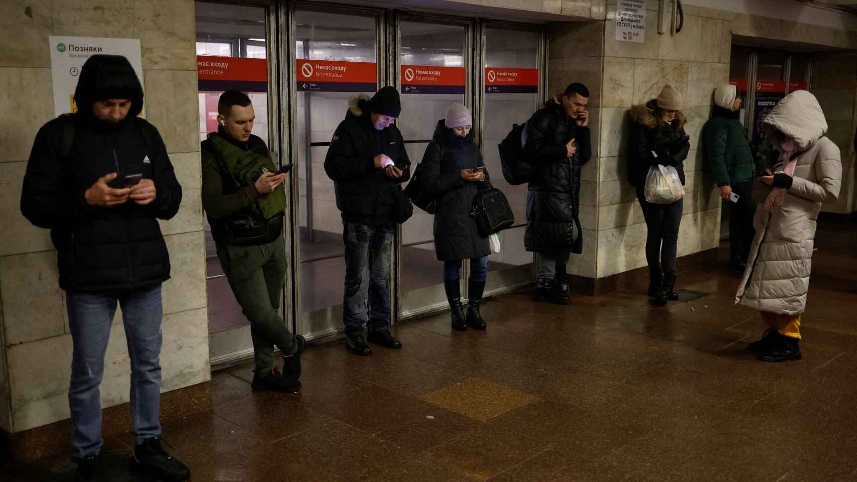 La gente usa Internet móvil junto a una estación de metro después de que la infraestructura civil crítica fuera golpeada por los ataques con misiles rusos en Kiev