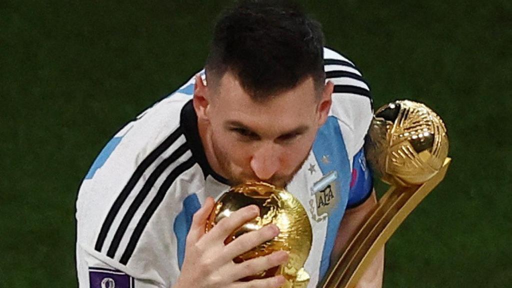Leo Messi, con el Balón de Oro del Mundial en la mano, besa la copa del mundo.