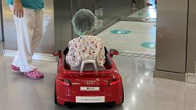 Un niño en un coche de juguete en el hospital.