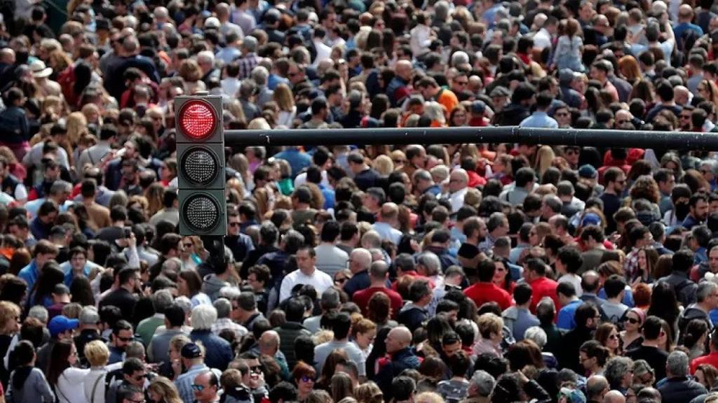 Una multitud con un semáforo rojo en primer plano, en imagen de archivo.