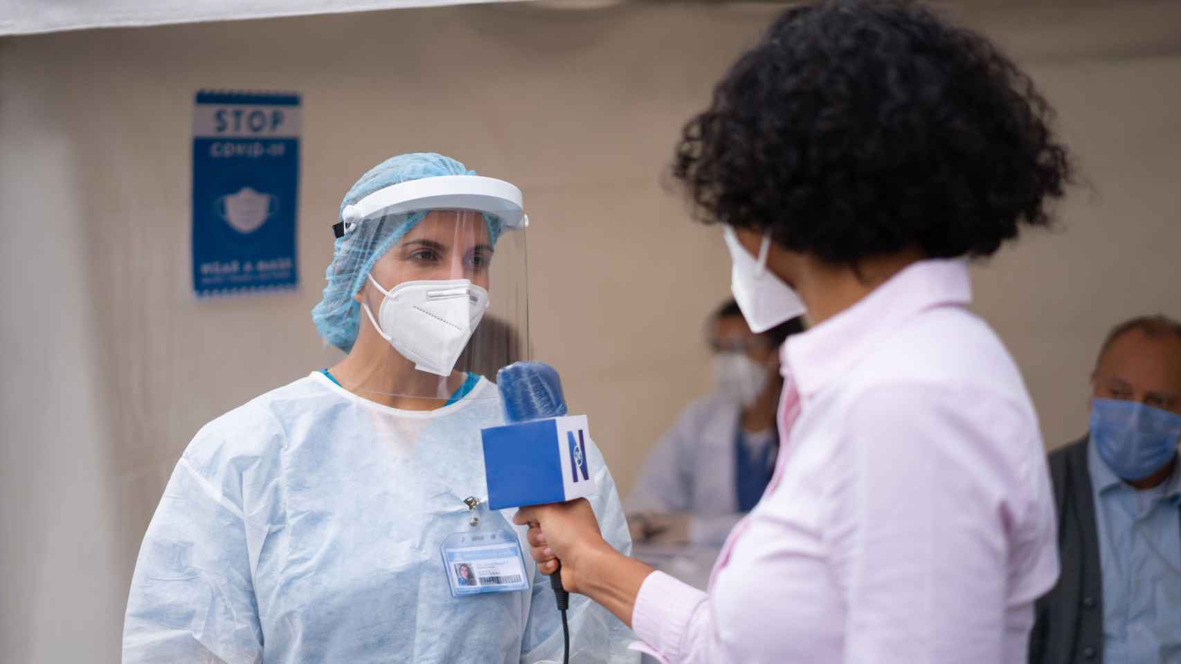 Una periodista entrevistando a un sanitario en un puesto de vacunación Covid-19.