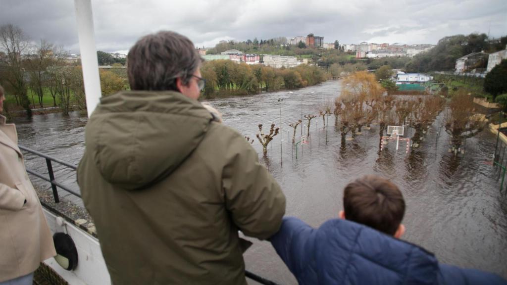 Un hombre y un niño observan la crecida del río Miño debido a las lluvias en Lugo.