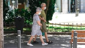 Una pareja de ancianos con mascarilla camina por la calle