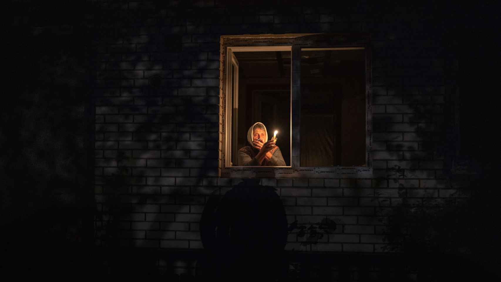 Una mujer enciende una vela en su casa sin luz, en la región de Kiev, tras la oleada de ataques con misiles rusos.