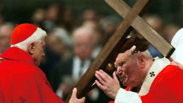 El papa Juan Pablo II besando el crucifijo de madera que sostiene el entonces cardenal Joseph Ratzinger, durante la Misa de la Pasión del Viernes Santo, en la Basílica de San Pedro, en el Vaticano, el 9 de abril de 2004
