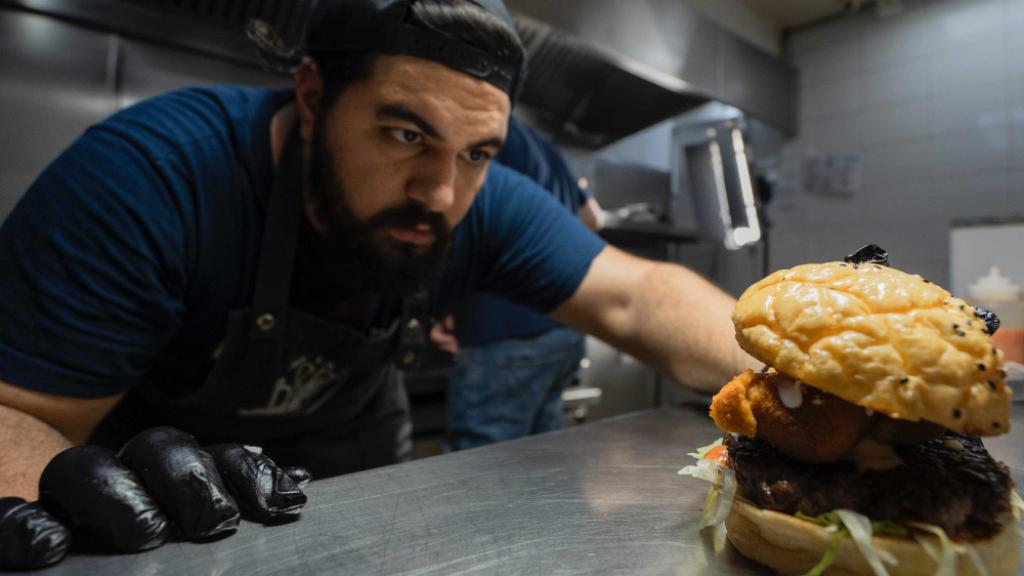 Un miembro de la familia Cocchia, que está detrás de La Birra Bar, con una hamburguesa.