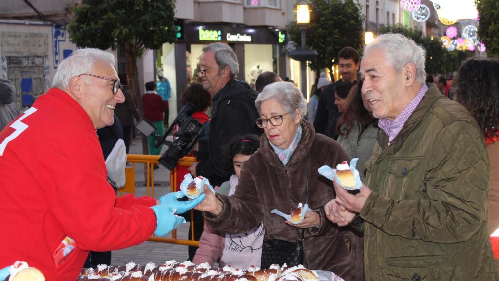 Un voluntario de Cruz Roja entrega dos pedazos de roscón.