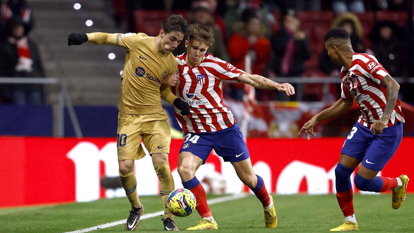 Gavi defiende un balón ante la presión de los jugadores del Atlético.
