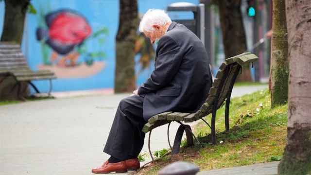 Un anciano descansa en un banco.