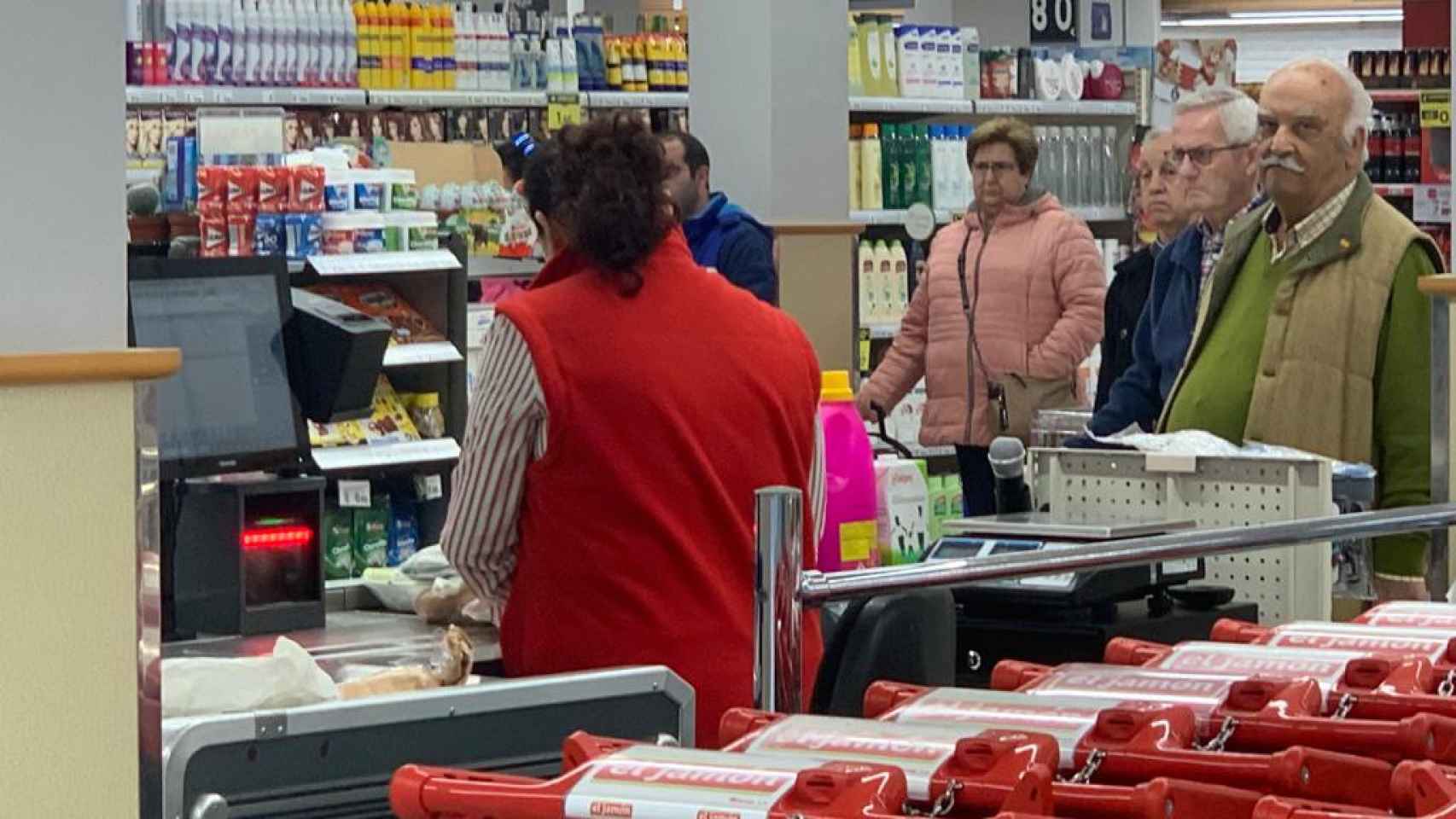 Un grupo de clientes guarda la cola para pasar por caja en un supermercado.