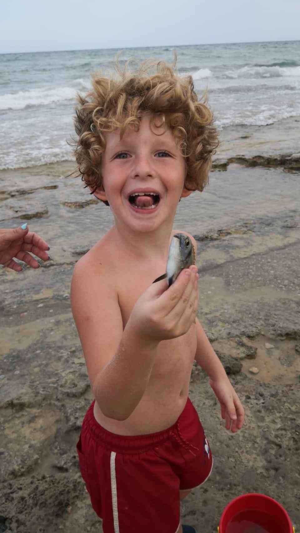 Martín, en una playa alicantina, mostrando un pez.
