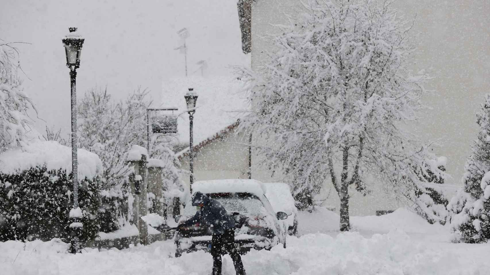 Una persona intenta limpiar de nieve para poder sacar su vehículo de una calle de la localidad de Espinal.