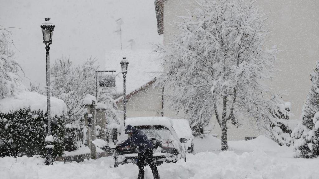 Una persona intenta limpiar de nieve para poder sacar su vehículo de una calle de la localidad de Espinal.