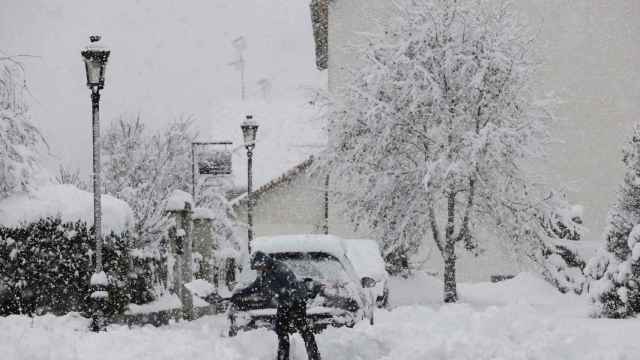 Una persona intenta limpiar de nieve para poder sacar su vehículo de una calle de la localidad de Espinal.