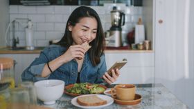 Imagen de archivo mujer de mirando su móvil mientras come