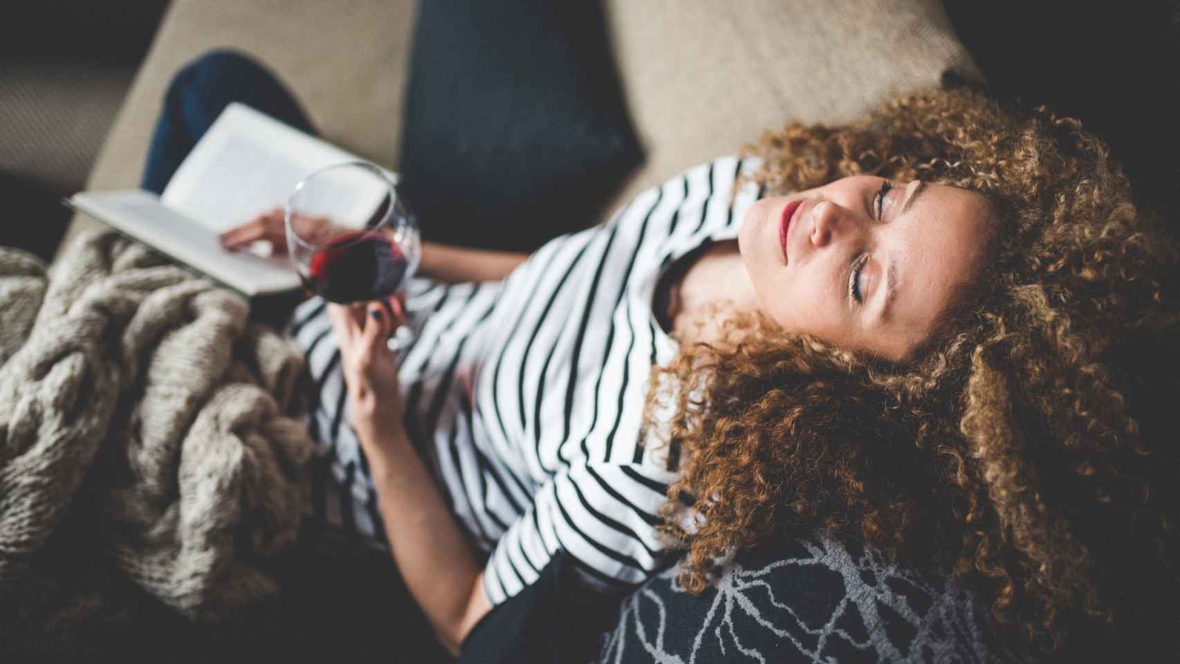 Imagen de archivo de mujer con copa de vino y leyendo