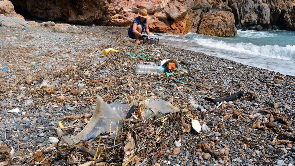 Una voluntaria limpia una playa.