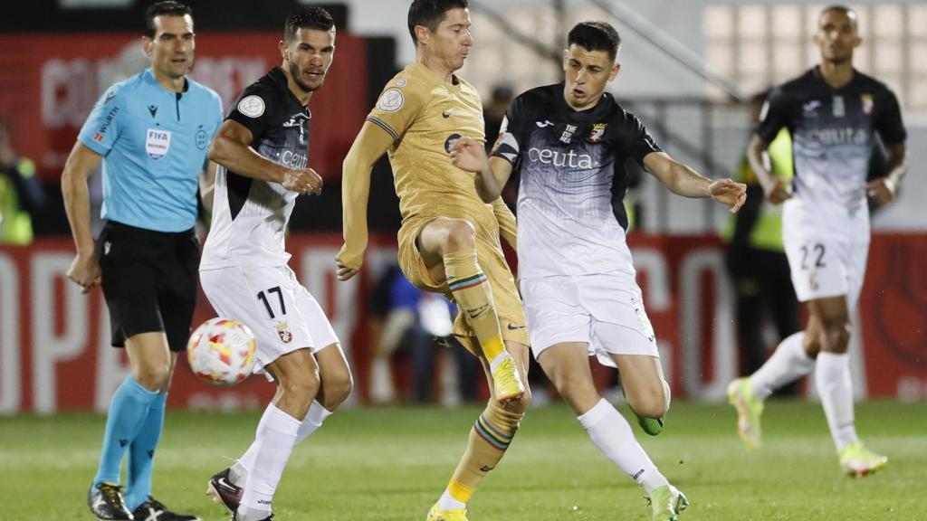 Robert Lewandowski pelea un balón con la defensa del AD Ceuta