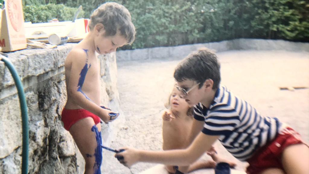 Pablo Ibáñez, pintando a su hermano Juan de azul para que fuera un pitufo, mientras los observa su hermana María José.