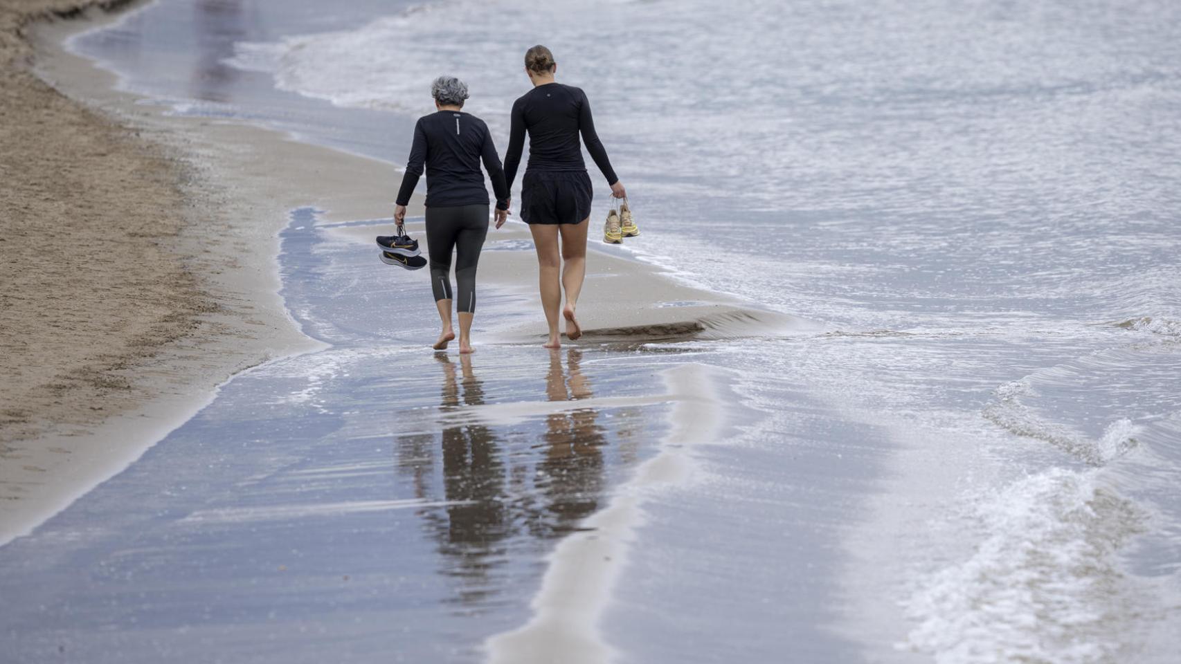 Dos personas caminan por una playa valenciana a principios de enero.