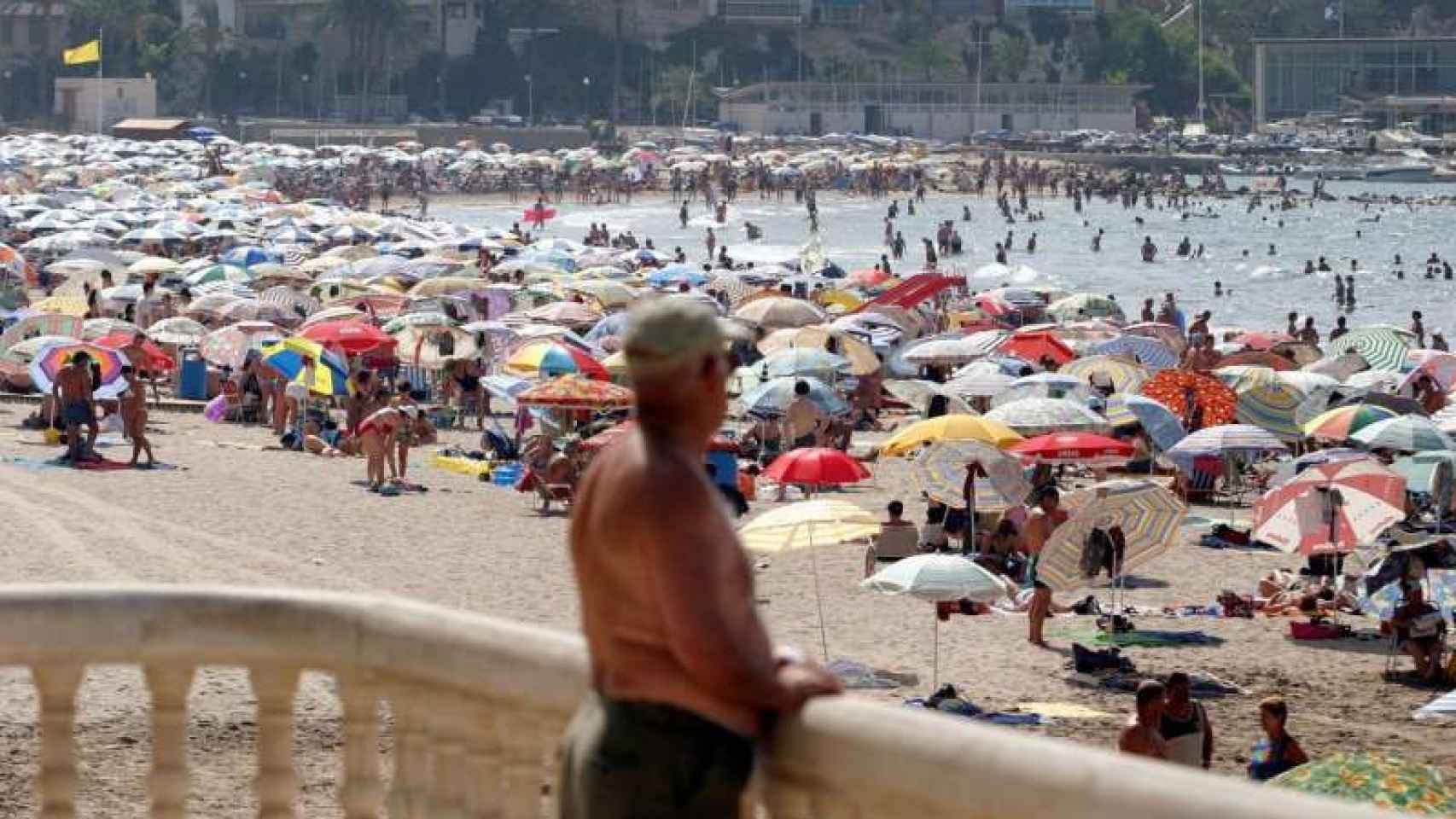 Un hombre observa la playa de Poniente de Benidorm llena de gente, en imagen de archivo.