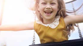 Una niña jugando feliz en un columpio.