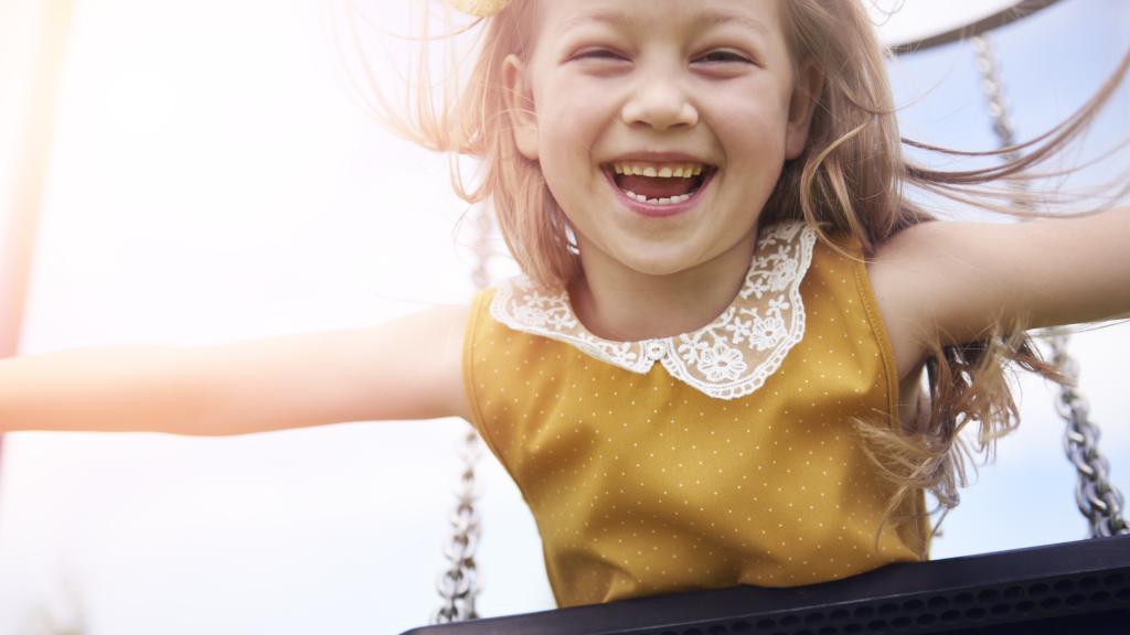 Una niña jugando feliz en un columpio.