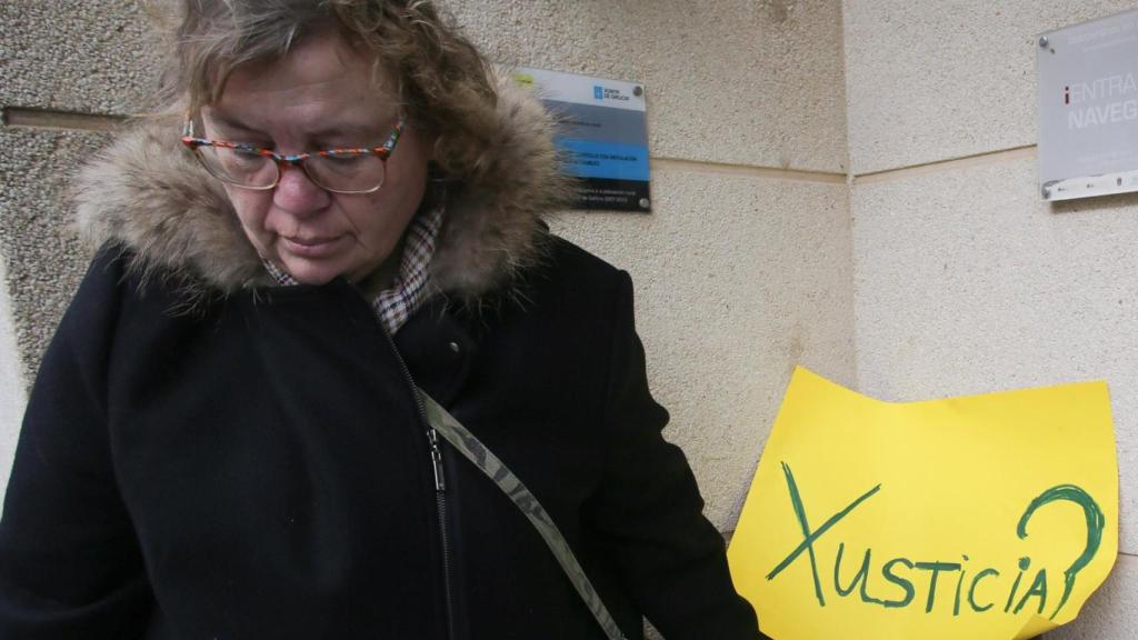 Una mujer junto a un cartel en la basura en una concentración de repulsa por el caso de la niña violada en Baleira.