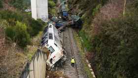 Dos hombres realizan las labores de retirada del tren accidentado en Lalín (Pontevedra).