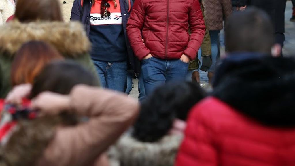 Varias personas bien abrigadas pasean por las calles de Toledo.