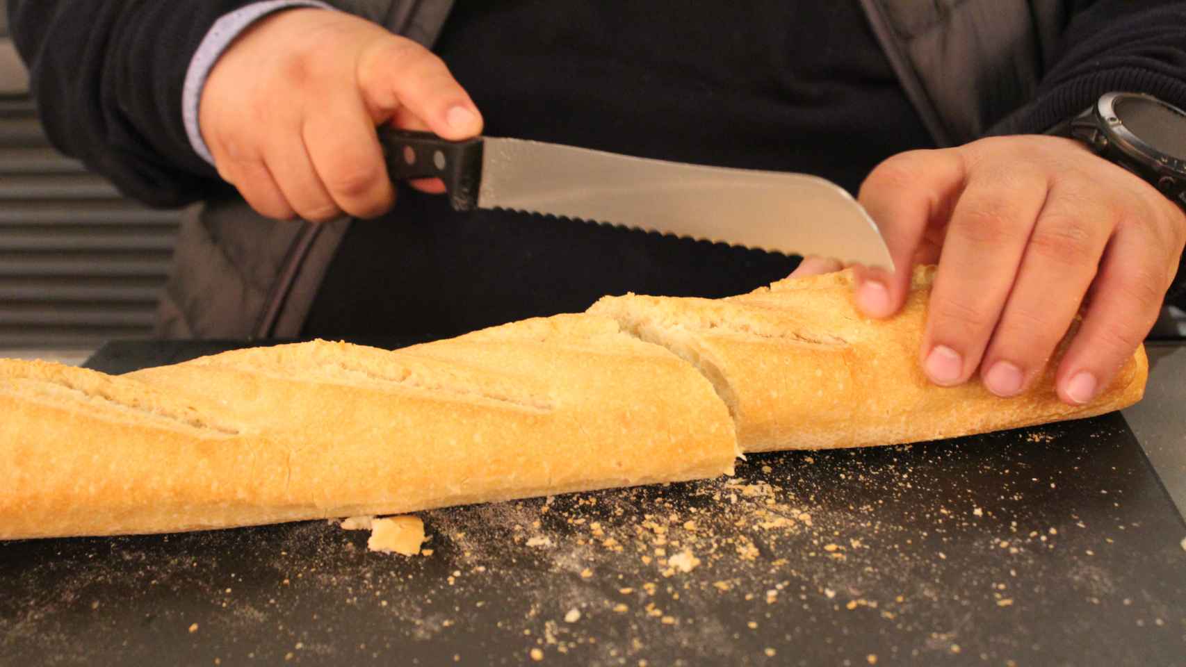 El panadero John Torres, cortando con habilidad la barra de Mercadona para analizarla.