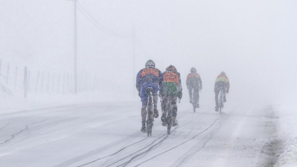 Unos ciclistas en una carretera con nieve, en una imagen de archivo.